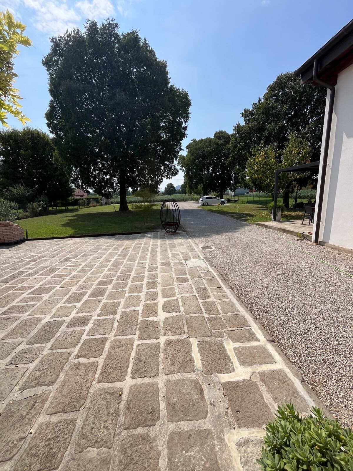 A paved driveway leading to a building with a covered outdoor seating area.