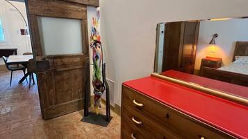 A room with a wooden dresser, a bed with a nightstand, and a mural on the wall.