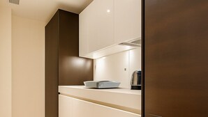 A modern kitchen with wooden flooring, white cabinetry, and a stainless steel appliance. - Still Life Moorgate Deluxe (London)