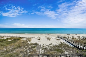 A beach with a wooden boardwalk and a fence.