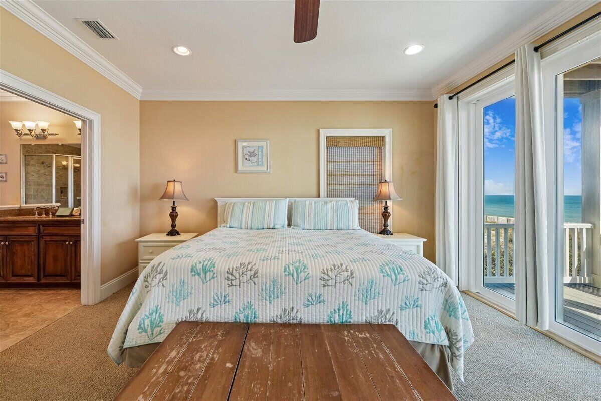 A bedroom with a bed, bedside lamps, a window with a view, and a wooden bench.