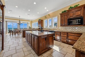 A spacious kitchen with a large island, wooden cabinets, and a view to the outside.
