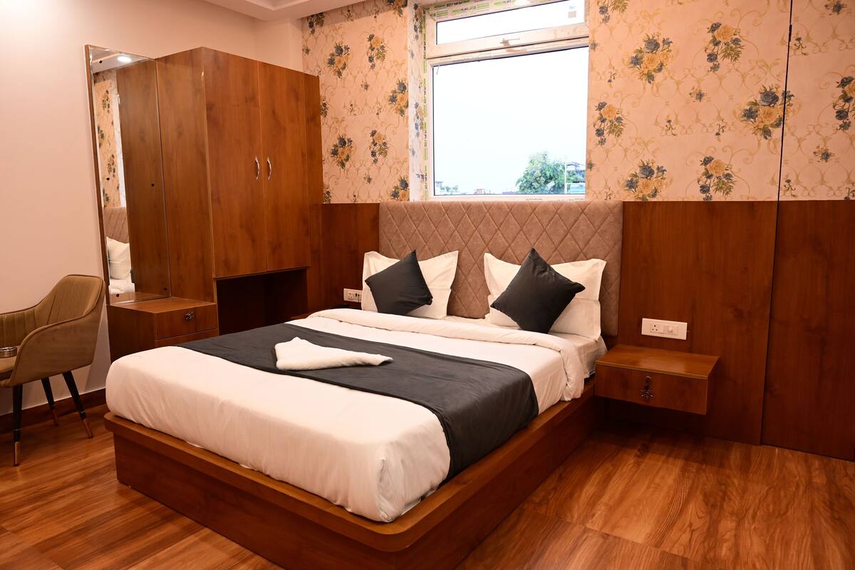 A bedroom with a large bed, a wardrobe, a bedside table, and a chair.