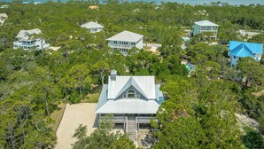 A coastal property with multiple houses surrounded by dense forest, a beach, and a view of the ocean. - Welcome to Sun Treader! (St. George Island)