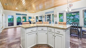 A spacious kitchen with a large island, white cabinetry, and a wooden ceiling. - Welcome to Sun Treader! (St. George Island)