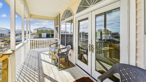 Eine überdachte Veranda mit Blick auf Strand und Häuser.