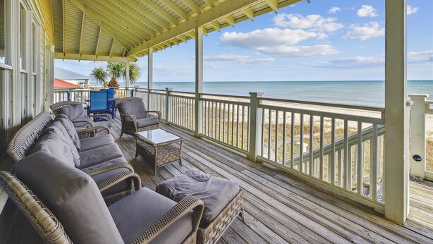 A covered outdoor seating area with wicker furniture and a view of the beach. - Welcome to Salty Dawg! (Eastpoint)