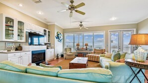 A spacious living room with a fireplace, a dining area, and a kitchen with white cabinets and a TV. - Welcome to Salty Dawg! (Eastpoint)