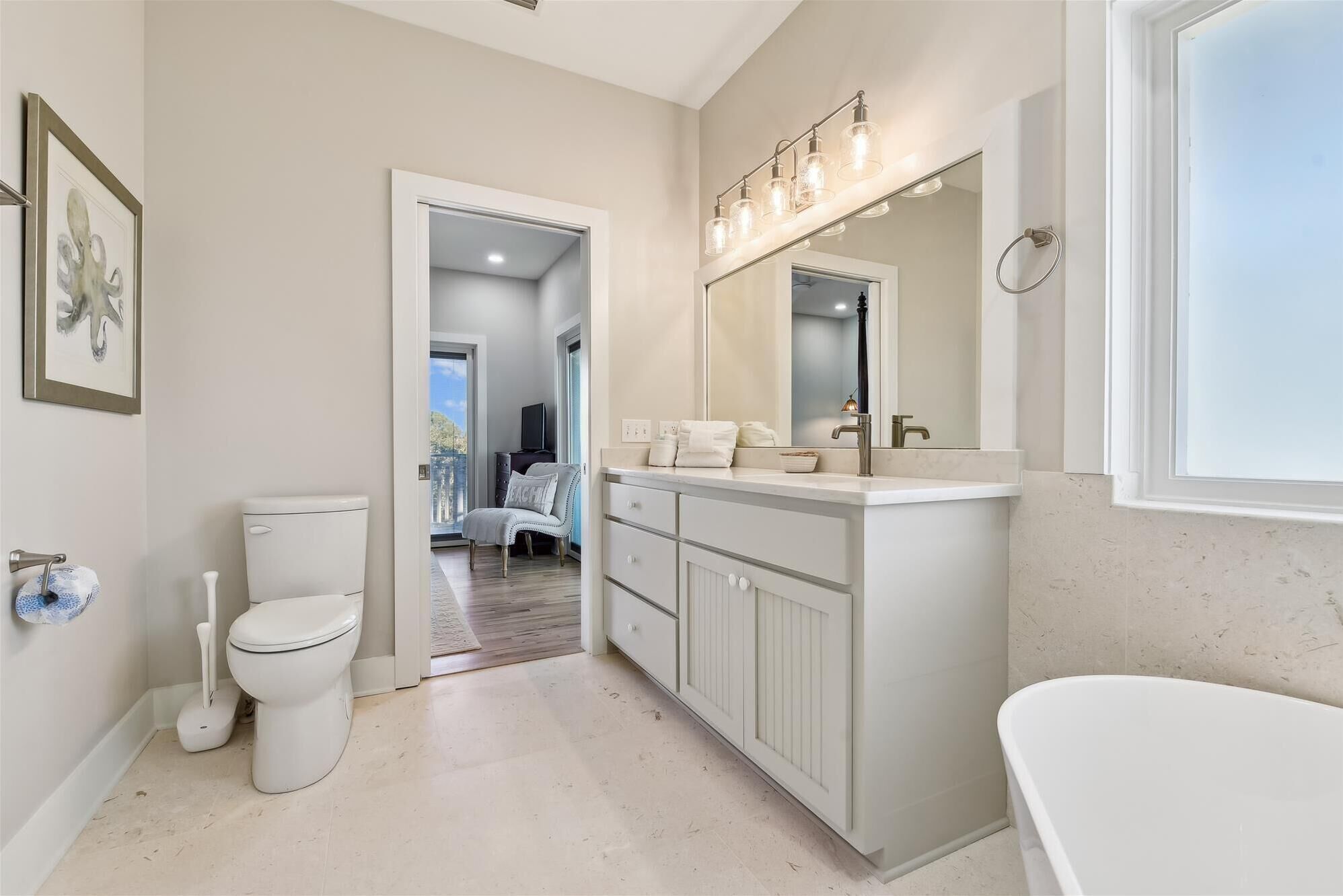 A modern bathroom with a large vanity, a freestanding bathtub, and a toilet.