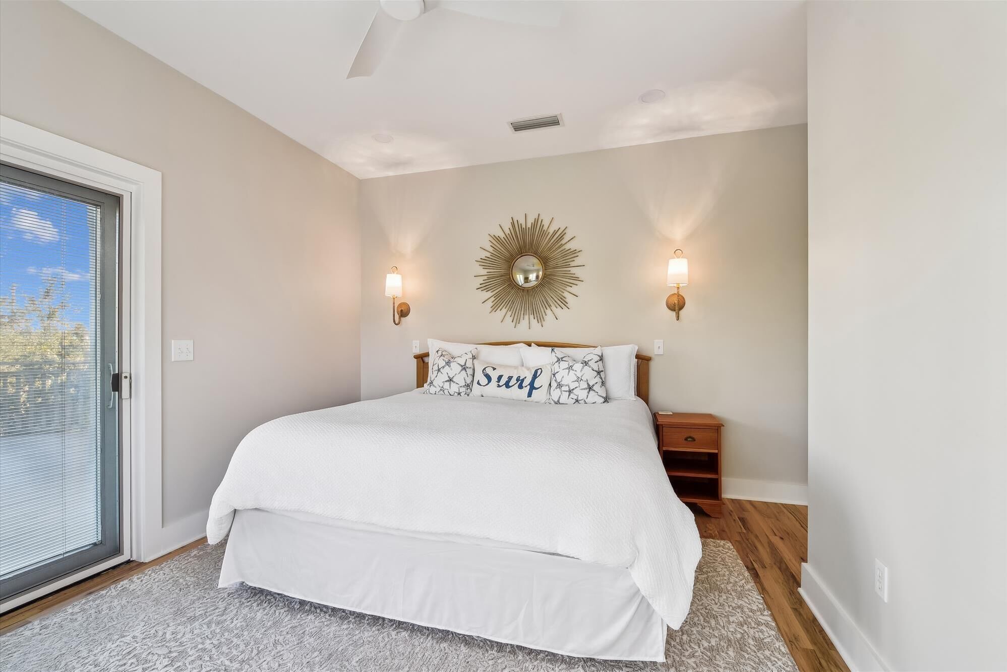 Un dormitorio con una cama grande, un ventanal corredero y dos luces fijadas a la pared.
