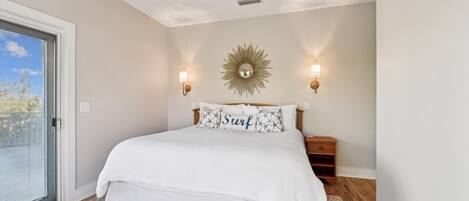 Un dormitorio con una cama grande, un ventanal corredero y dos luces fijadas a la pared.