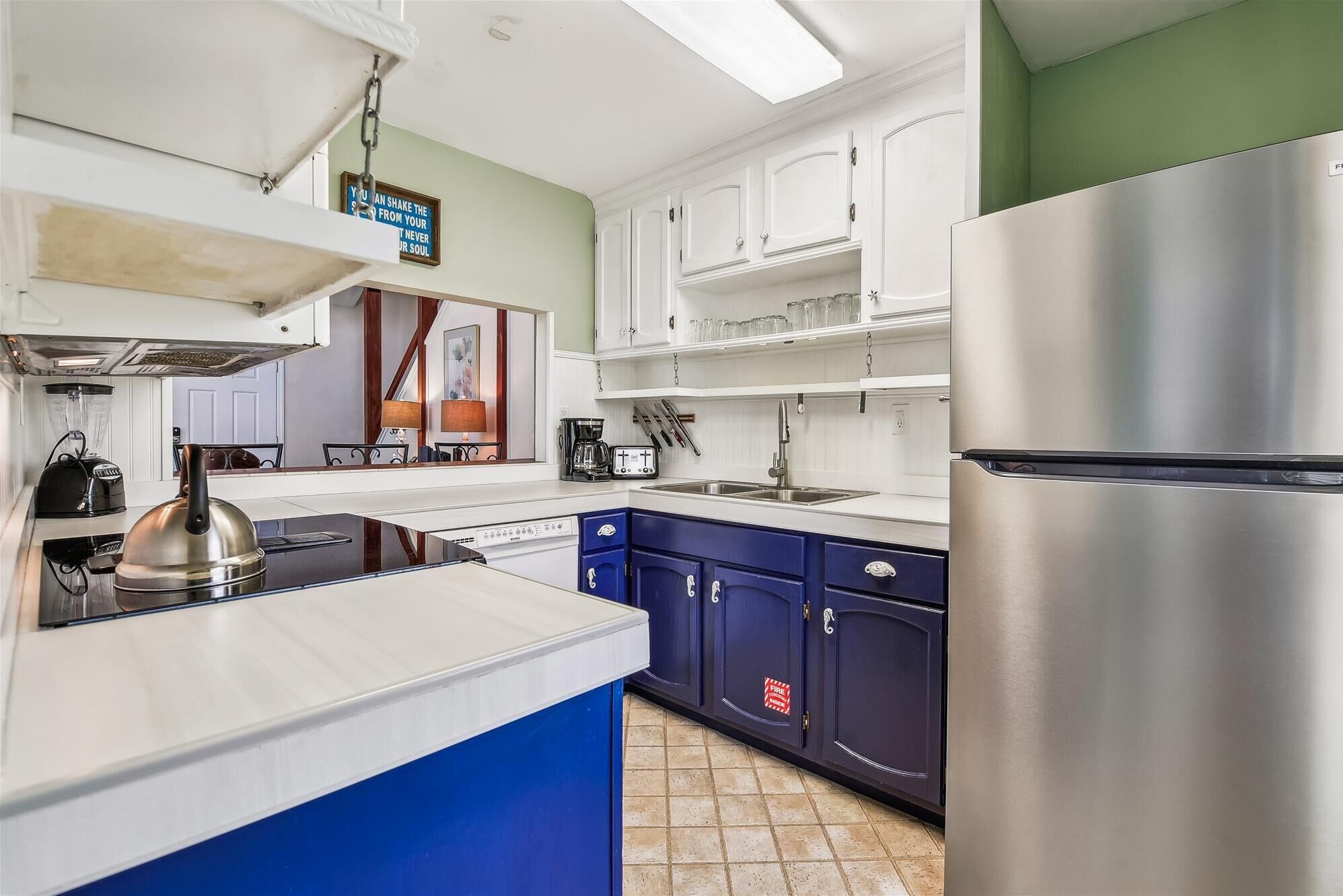 A modern kitchen with white cabinets, a stainless steel refrigerator, and a blue island.