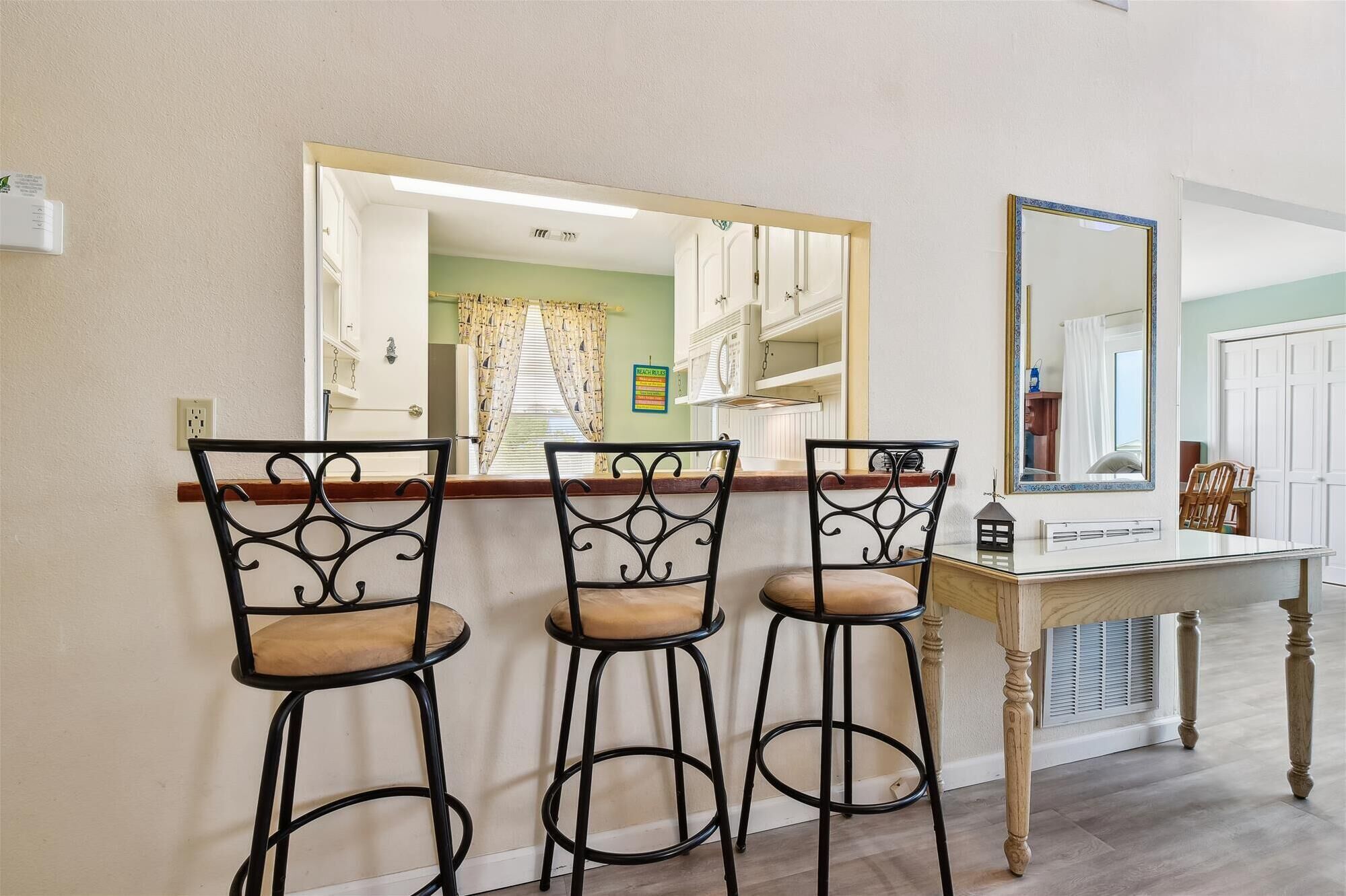 Un coin bar avec trois tabourets, un miroir et une table.