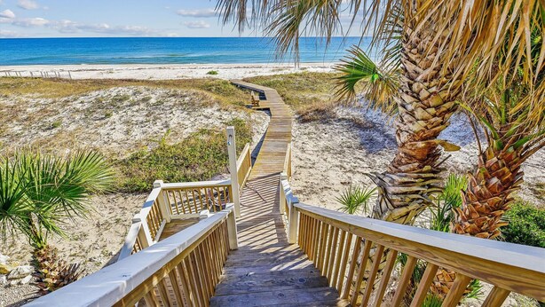 Un escalier en bois mène à une plage d’où l ’on a une vue dégagée sur l’océan.