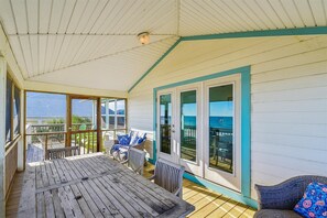 A covered outdoor area with a wooden deck, a table, chairs, and a view of the ocean. - Welcome to Watercolor! (St. George Island)