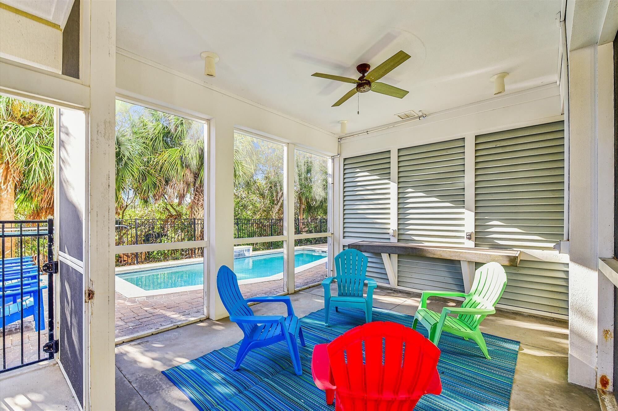 A covered patio with a pool, outdoor chairs, and a ceiling fan.