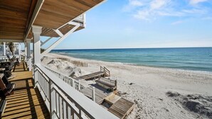 A beachside balcony with wooden decking and railings, overlooking a sandy beach and the ocean. - Welcome to DUNE IT RIGHT! (St. George Island)