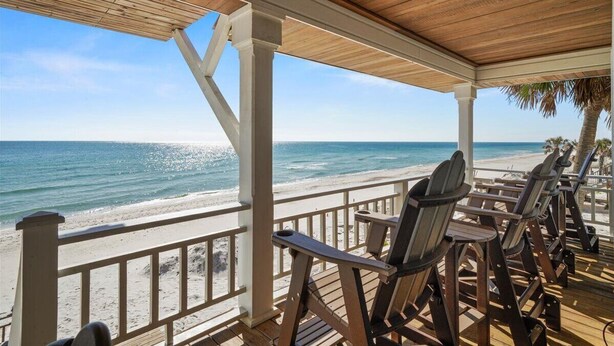 A covered deck with wooden chairs facing a beach. - Welcome to DUNE IT RIGHT! (St. George Island)