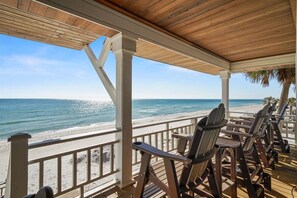 A covered deck with wooden chairs facing a beach. - Welcome to DUNE IT RIGHT! (St. George Island)