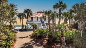 A beachfront property with a two-story building, a staircase leading to the upper floor, and a paved pathway. - Welcome to DUNE IT RIGHT! (St. George Island)