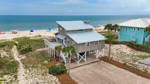 A two-story beachfront house with a covered deck and a view of the beach and ocean. - Wander from the cool shade of the screened porch to the sun deck with your favorite book! (St. George Island)