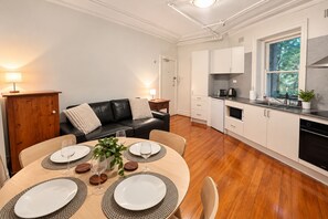 A modern kitchen with white cabinets, a black countertop, and a window with a view of greenery.