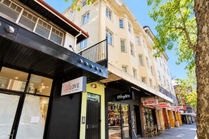 A street view with a building featuring a black awning and a sign for 'Love Hair Nails Beauty'.