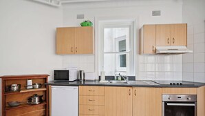 A kitchen with wooden cabinets, a white dishwasher, a microwave, a sink, and an oven.