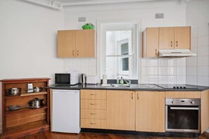 A kitchen with wooden cabinets, a white dishwasher, a microwave, a sink, and an oven.