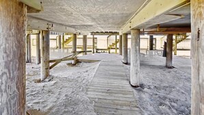 An empty, open interior space with a wooden deck and concrete pillars. - Welcome to Ocean Mile H-8! (St. George Island)
