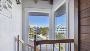 A view from a balcony with a wooden railing, overlooking a residential area with houses and a clear sky. - Welcome to Island Dream, where dreams come true! (St. George Island)