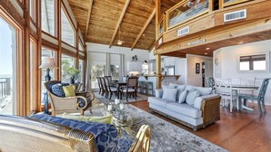 A spacious living area with a high ceiling, wooden beams, a dining area, and a kitchen. - Welcome to Island Dream, where dreams come true! (St. George Island)