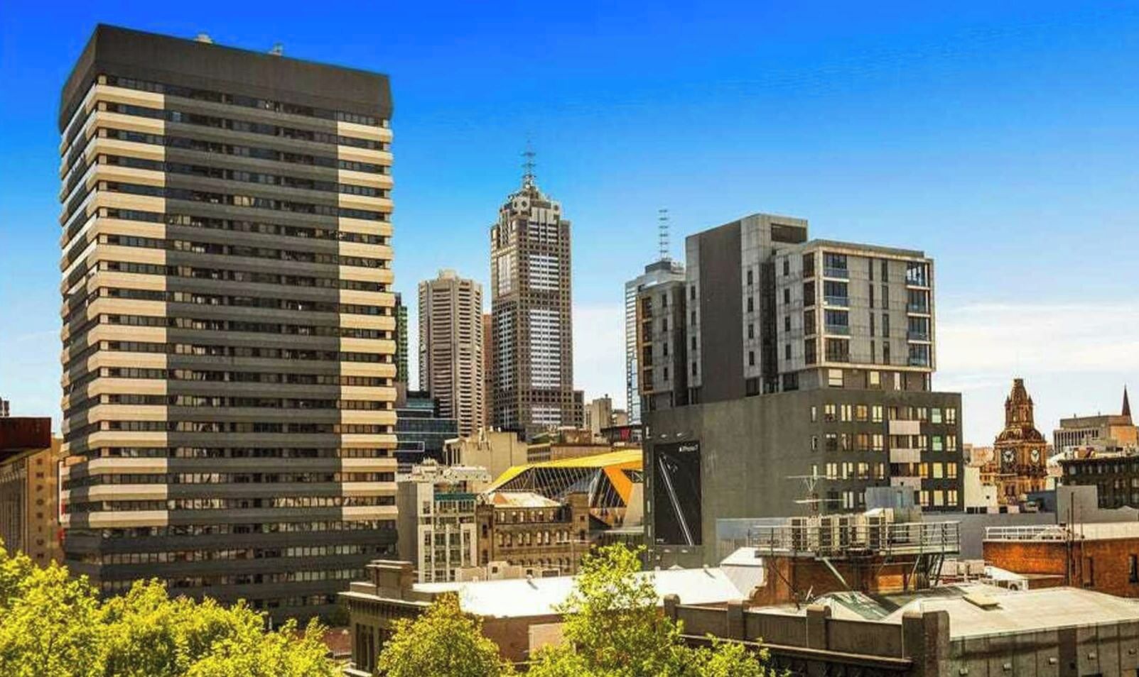 Un paysage urbain avec des immeubles modernes de grande hauteur, dont l’un présente une structure incurvée particulière et l’autre une façade plate.