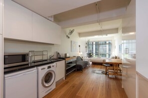 A compact kitchen with a washing machine, a microwave, and a sink.