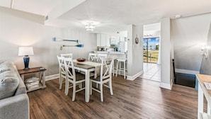 A modern living room with a dining area, wooden flooring, and a view of the backyard. - Welcome to Villa E-5! (St. George Island)
