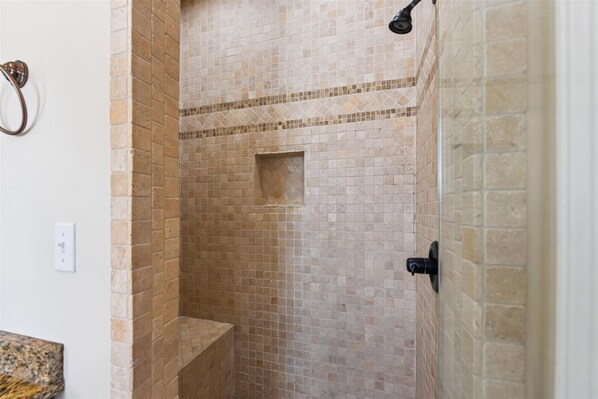 Un espace douche avec des murs carrelés et un banc intégré.