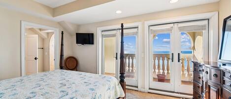 Une chambre à coucher comprenant un lit, une commode, un téléviseur et un ventilateur de plafond.