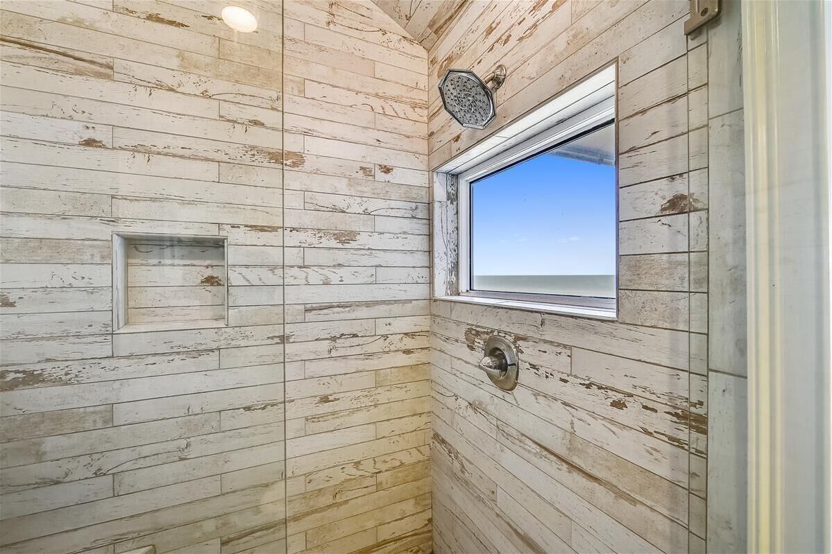 Un baño pequeño y rústico con paredes de madera, una ventana y un cabezal de ducha.