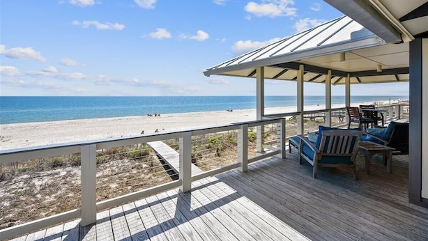 Una terraza de madera con vista a la playa y al océano.