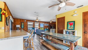 A spacious kitchen with wooden accents, a dining area with benches, and a view of the outdoors. - Welcome to Brief Escape! (St. George Island)