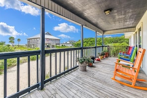 A wooden deck with a railing, potted plants, and colorful chairs. - Welcome to Brief Escape! (St. George Island)