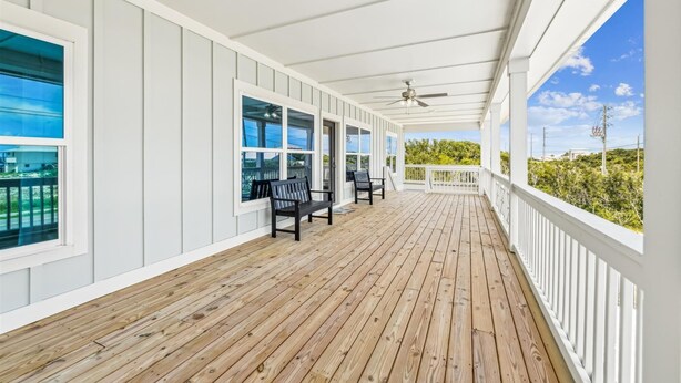 A covered porch with wooden flooring, white railings, and black chairs. - Welcome to Anchors Up! (St. George Island)