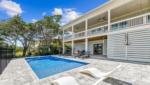 A swimming pool with lounge chairs, a covered patio, and a two-story building with a balcony. - Welcome to Anchors Up! (St. George Island)
