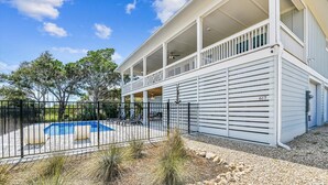 A two-story house with a covered balcony, a swimming pool, and a fenced yard. - Welcome to Anchors Up! (St. George Island)