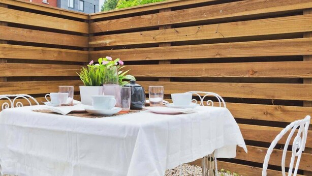A table set with white tablecloth, white chairs, and a potted plant. - Charming Riverside Apartment Minutes from City (Dublin)