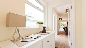 A hallway with a window, a lamp, a vase, and a magazine on a counter. - Charming Riverside Apartment Minutes from City (Dublin)