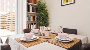 A dining area with a table set for four, surrounded by bookshelves, a potted plant, and a framed picture on the wall. - Charming Riverside Apartment Minutes from City (Dublin)