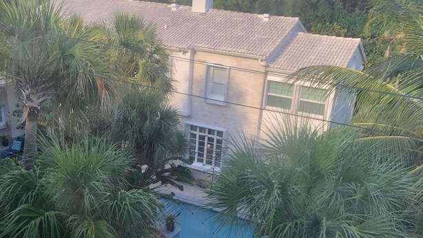 Una casa con piscina rodeada de palmeras.