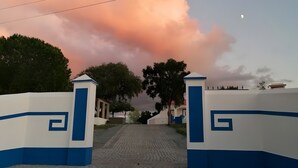 Una entrada pavimentada con una puerta, cielo despejado y una luna creciente.