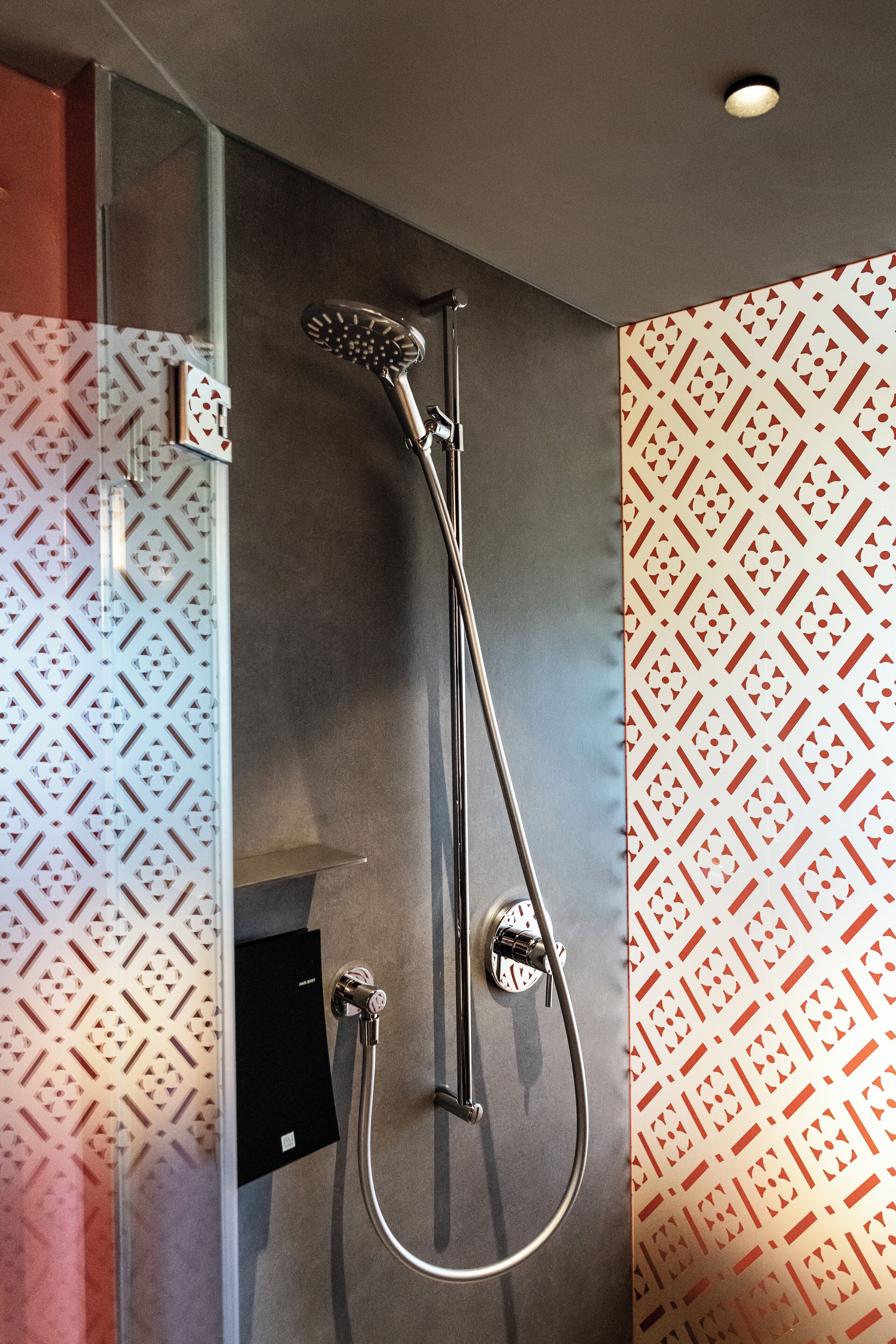 Una ducha con cabezal de ducha manual y grifo de pared.